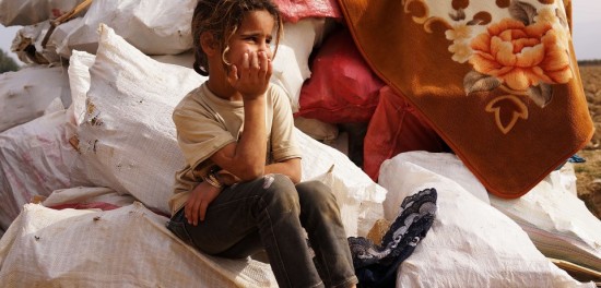 MAJDAL ANJAR, LEBANON - NOVEMBER 12: A Syrian girl sits on bags of firewood in a makeshift camp for Syrian refugees only miles from the border with Syria in the Bekaa Valley on November 12, 2013 in Majdal Anjar, Lebanon. As the war in neighboring Syria drags on for a third year, Lebanon, a country of only 4 million people, is now home to the largest number of Syrian refugees who have fled the conflict. The situation is beginning to put huge social and political strains on Lebanon as there is currently no end in sight to the war in Syria. (Photo by Spencer Platt/Getty Images)